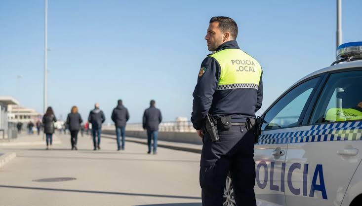 Agente de la Policía Local junto a un coche patrulla